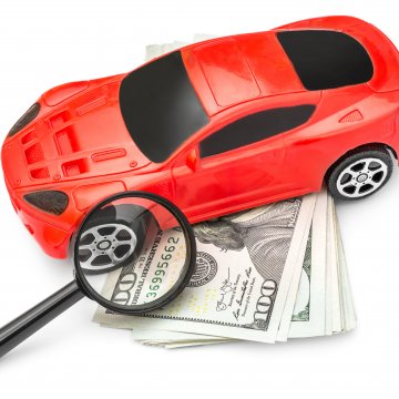 root car insurance price cost red car magnifying glass over dollar bills white background